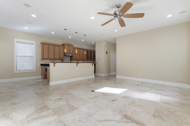 kitchen featuring decorative light fixtures, a breakfast bar area, ceiling fan, and a kitchen island