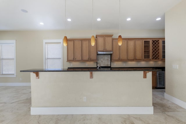 kitchen featuring a kitchen bar, decorative light fixtures, and an island with sink