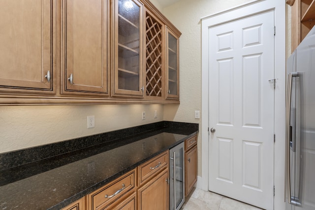 bar with light tile patterned floors, stainless steel fridge, dark stone counters, and wine cooler