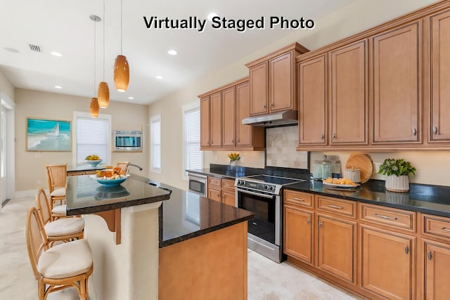 kitchen featuring a center island, a kitchen bar, stainless steel appliances, sink, and hanging light fixtures