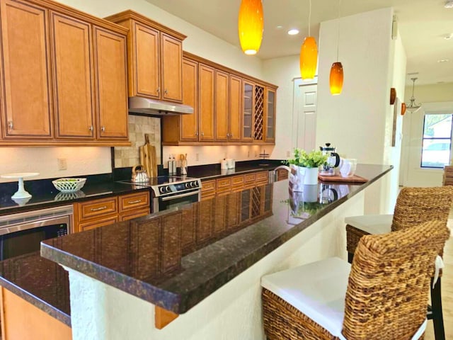 31 Beacon Point Dr, Santa Rosa Beach, FL 32459 - kitchen featuring range with electric cooktop, under cabinet range hood, brown cabinetry, a breakfast bar area, and glass insert cabinets