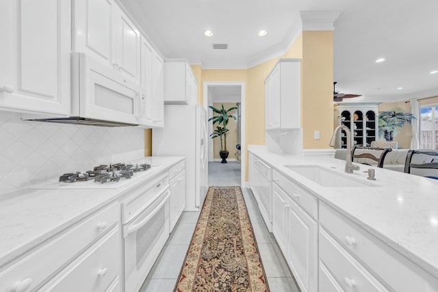 kitchen featuring sink, white appliances, light tile patterned floors, light stone countertops, and white cabinets