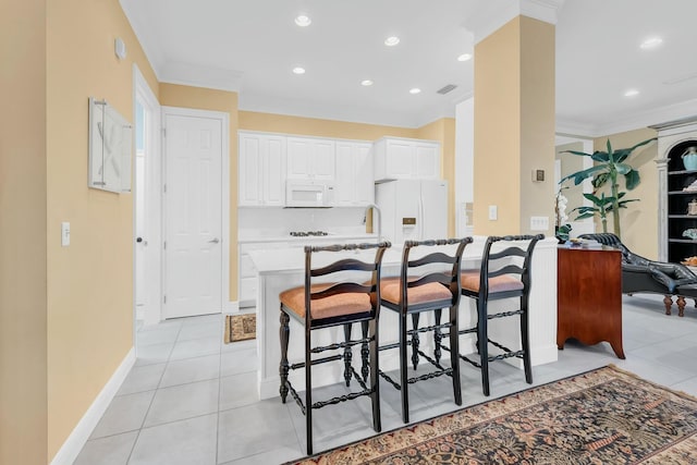 kitchen with white appliances, white cabinetry, a kitchen breakfast bar, ornamental molding, and light tile patterned flooring