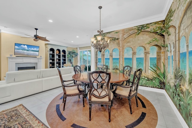 dining space featuring a tiled fireplace, light tile patterned flooring, ornamental molding, and ceiling fan with notable chandelier