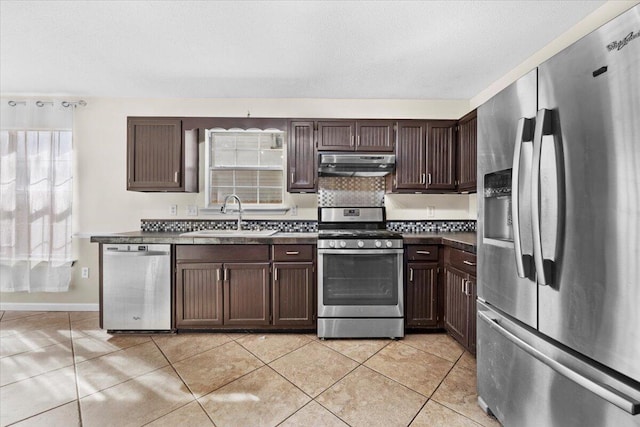 kitchen featuring a textured ceiling, dark brown cabinetry, stainless steel appliances, sink, and light tile patterned flooring