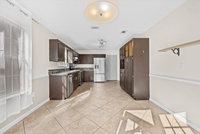 kitchen with light tile patterned floors, appliances with stainless steel finishes, sink, and dark brown cabinets