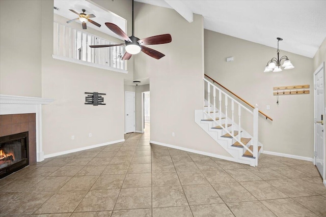 unfurnished living room with high vaulted ceiling, light tile patterned floors, a tile fireplace, and ceiling fan with notable chandelier