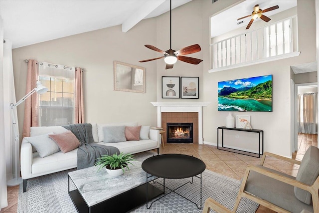 tiled living room with a tiled fireplace, ceiling fan, high vaulted ceiling, and beamed ceiling