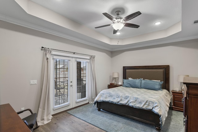 bedroom featuring ceiling fan, hardwood / wood-style floors, a tray ceiling, access to outside, and french doors