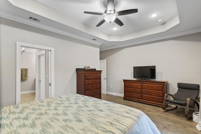 bedroom featuring crown molding, hardwood / wood-style flooring, a raised ceiling, and ceiling fan