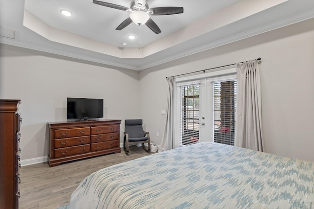 bedroom with light hardwood / wood-style flooring, access to exterior, ceiling fan, and a tray ceiling