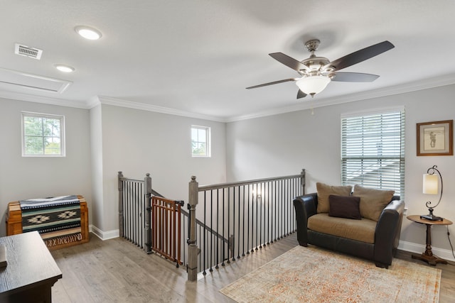 living area with a healthy amount of sunlight, ornamental molding, and light wood-type flooring