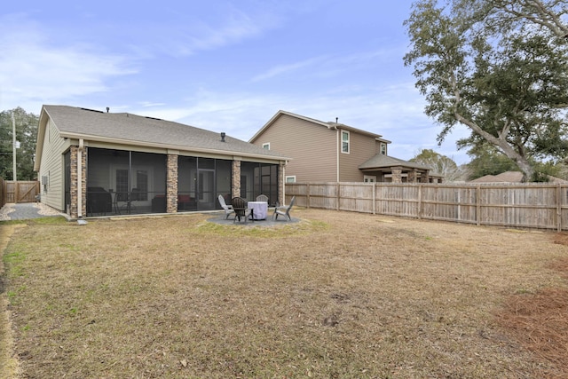 rear view of property featuring a yard, a sunroom, and an outdoor fire pit