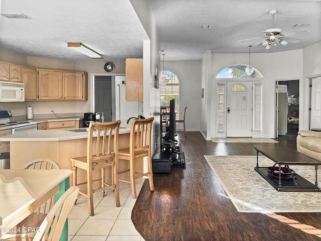 kitchen with light brown cabinets, white appliances, a peninsula, light countertops, and ceiling fan