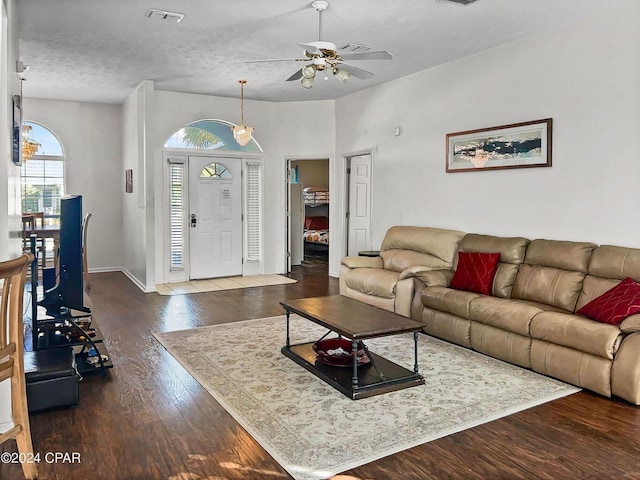 living area featuring visible vents, a textured ceiling, wood finished floors, baseboards, and ceiling fan