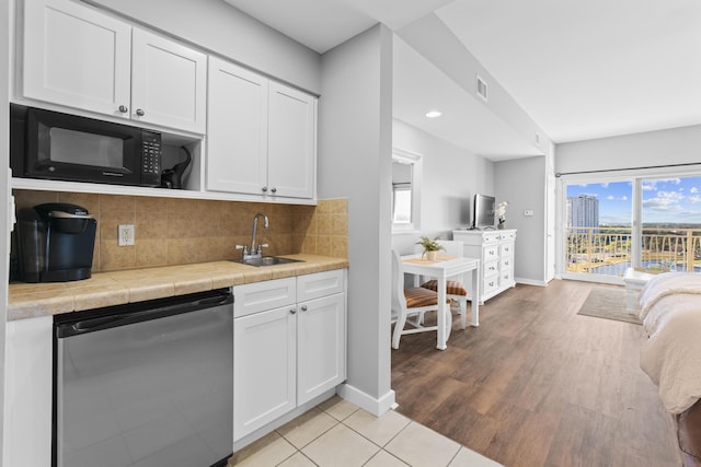 kitchen featuring sink, dishwashing machine, white cabinets, and tasteful backsplash