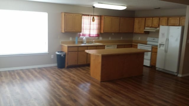 kitchen with dark hardwood / wood-style flooring, sink, white appliances, and a kitchen island