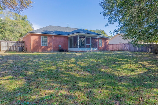 back of property featuring a sunroom, a lawn, and central AC unit