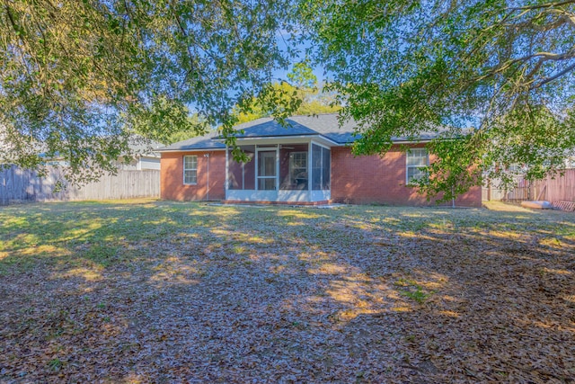 rear view of property with a sunroom and a lawn