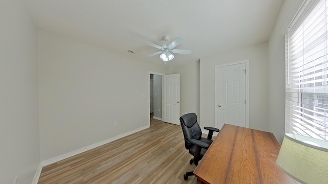 home office with light wood-type flooring and ceiling fan