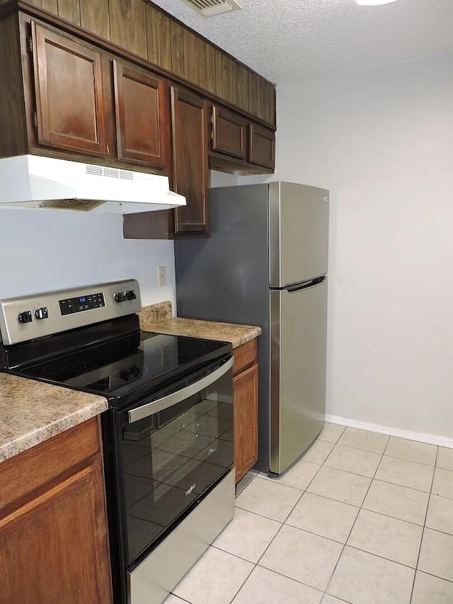 kitchen with light tile patterned floors, a textured ceiling, and appliances with stainless steel finishes