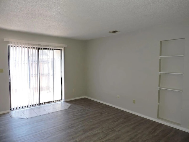 spare room featuring wood-type flooring and a textured ceiling