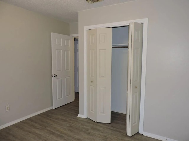 unfurnished bedroom featuring a textured ceiling, a closet, and hardwood / wood-style floors