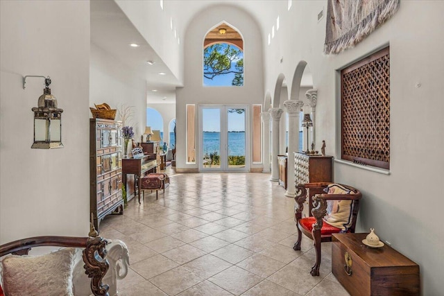 tiled entryway featuring a water view and a towering ceiling