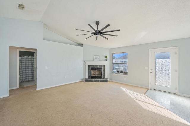 unfurnished living room with vaulted ceiling, ceiling fan, light colored carpet, and a tile fireplace