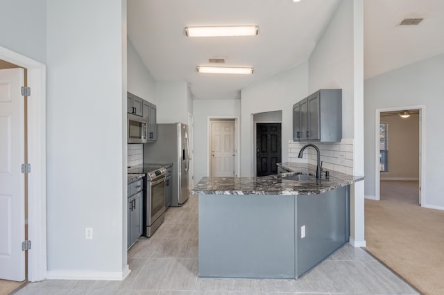 kitchen featuring kitchen peninsula, appliances with stainless steel finishes, gray cabinetry, tasteful backsplash, and sink