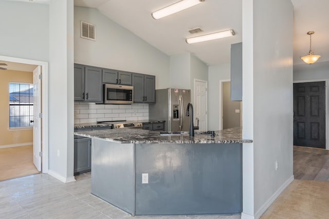 kitchen with hanging light fixtures, kitchen peninsula, dark stone countertops, and stainless steel appliances