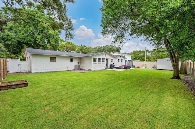 rear view of property with a storage shed, a yard, a patio, and central air condition unit