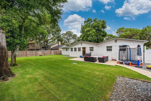 rear view of property with a patio, outdoor lounge area, a yard, and a trampoline