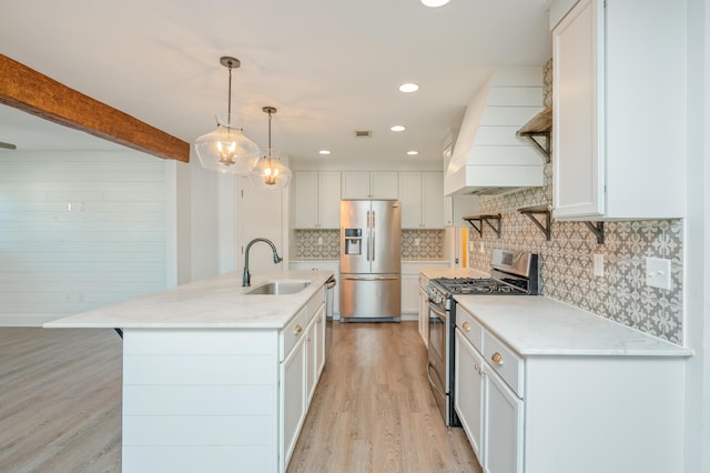 kitchen with decorative light fixtures, white cabinetry, an island with sink, sink, and stainless steel appliances