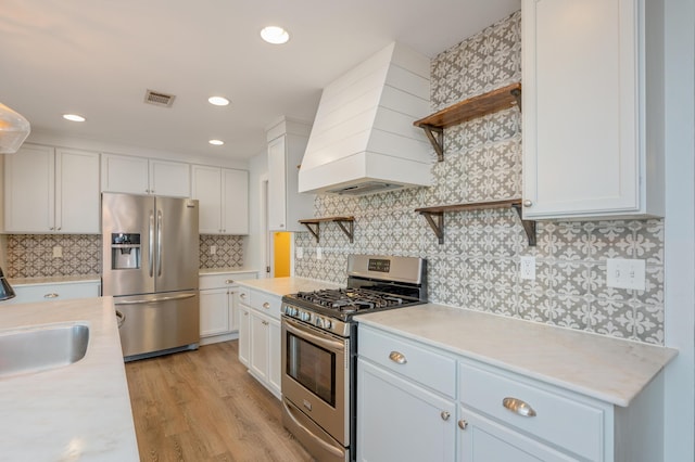 kitchen featuring sink, white cabinetry, custom range hood, stainless steel appliances, and decorative backsplash