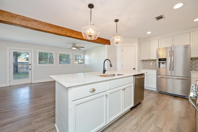 kitchen with sink, a kitchen island with sink, white cabinetry, beam ceiling, and stainless steel appliances