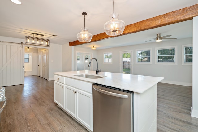 kitchen with white cabinetry, dishwasher, sink, a kitchen island with sink, and a barn door