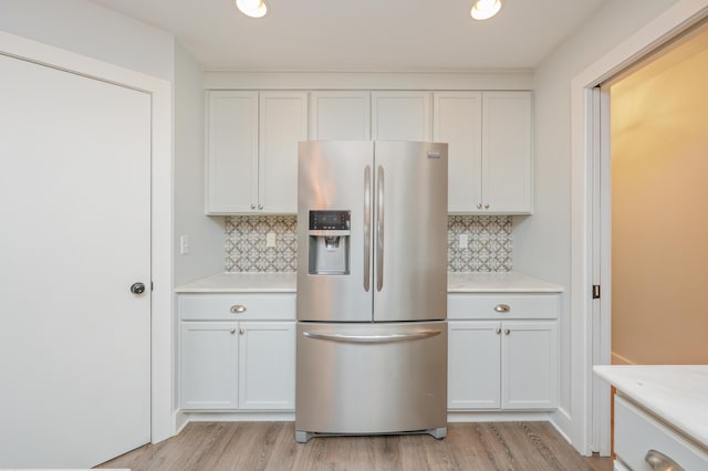 kitchen featuring stainless steel refrigerator with ice dispenser, light hardwood / wood-style flooring, decorative backsplash, and white cabinets