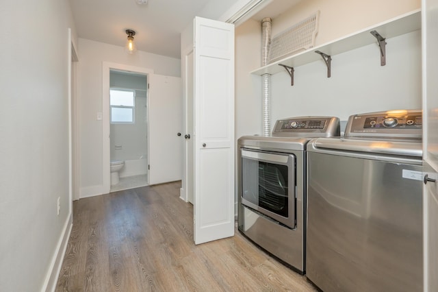 laundry area featuring separate washer and dryer and light hardwood / wood-style floors