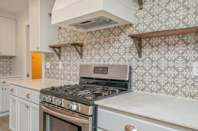 kitchen with stainless steel gas stove, white cabinetry, tasteful backsplash, and custom range hood