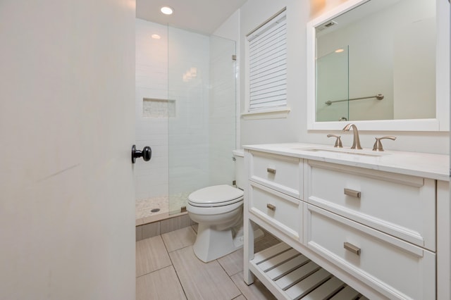 bathroom featuring tiled shower, vanity, and toilet