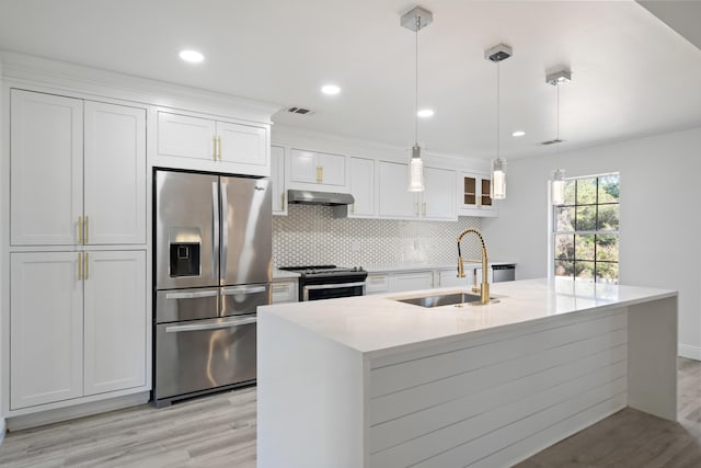 kitchen featuring white cabinets, appliances with stainless steel finishes, decorative light fixtures, an island with sink, and sink