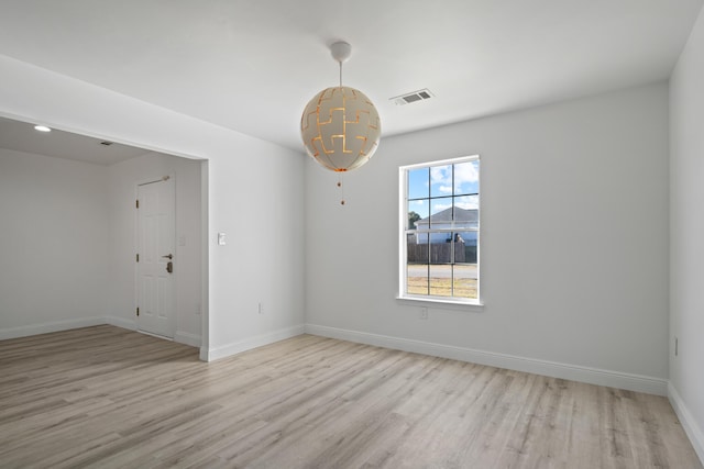 empty room with an inviting chandelier and light hardwood / wood-style flooring