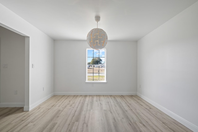 empty room featuring light hardwood / wood-style floors and a chandelier