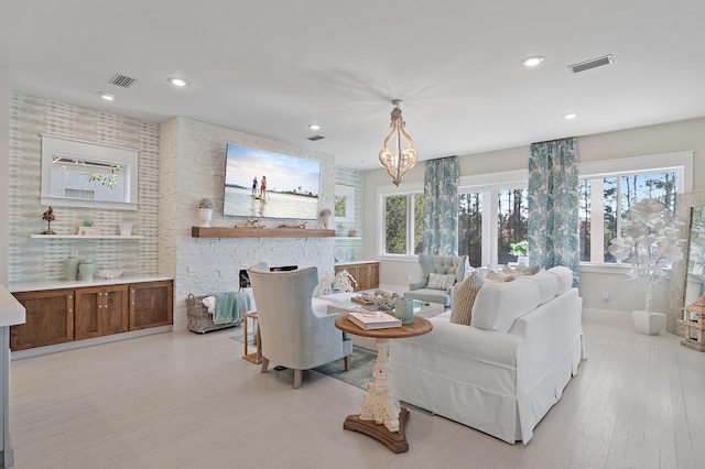 living area with a stone fireplace, recessed lighting, visible vents, and light wood-style floors