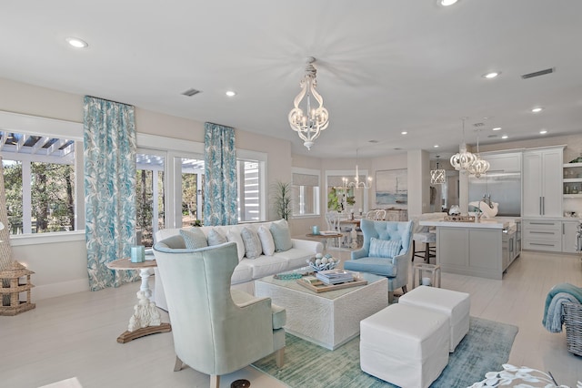 living room featuring visible vents, baseboards, light wood-style flooring, a chandelier, and recessed lighting