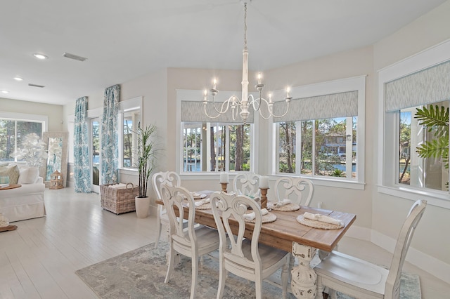 dining space featuring a notable chandelier, baseboards, visible vents, and a healthy amount of sunlight