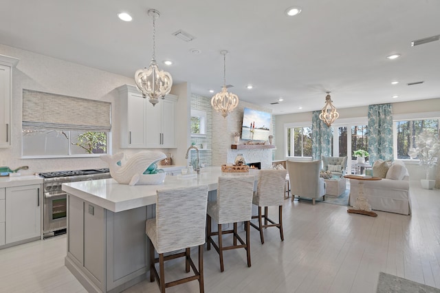 kitchen featuring light wood finished floors, plenty of natural light, visible vents, open floor plan, and high end stove