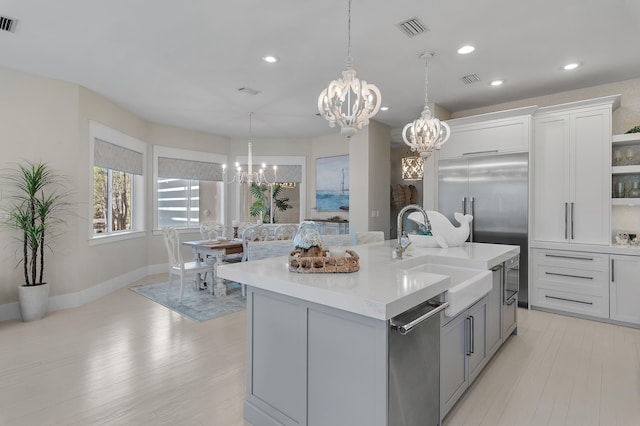 kitchen featuring a notable chandelier, open shelves, light countertops, visible vents, and a sink