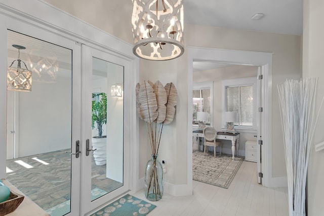 entryway with a chandelier, french doors, and baseboards